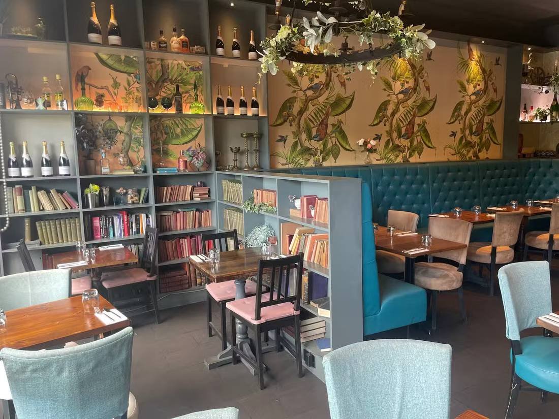 The main dining room at Park's Edge with teal velvet banquettes and hand-painted botanical mural